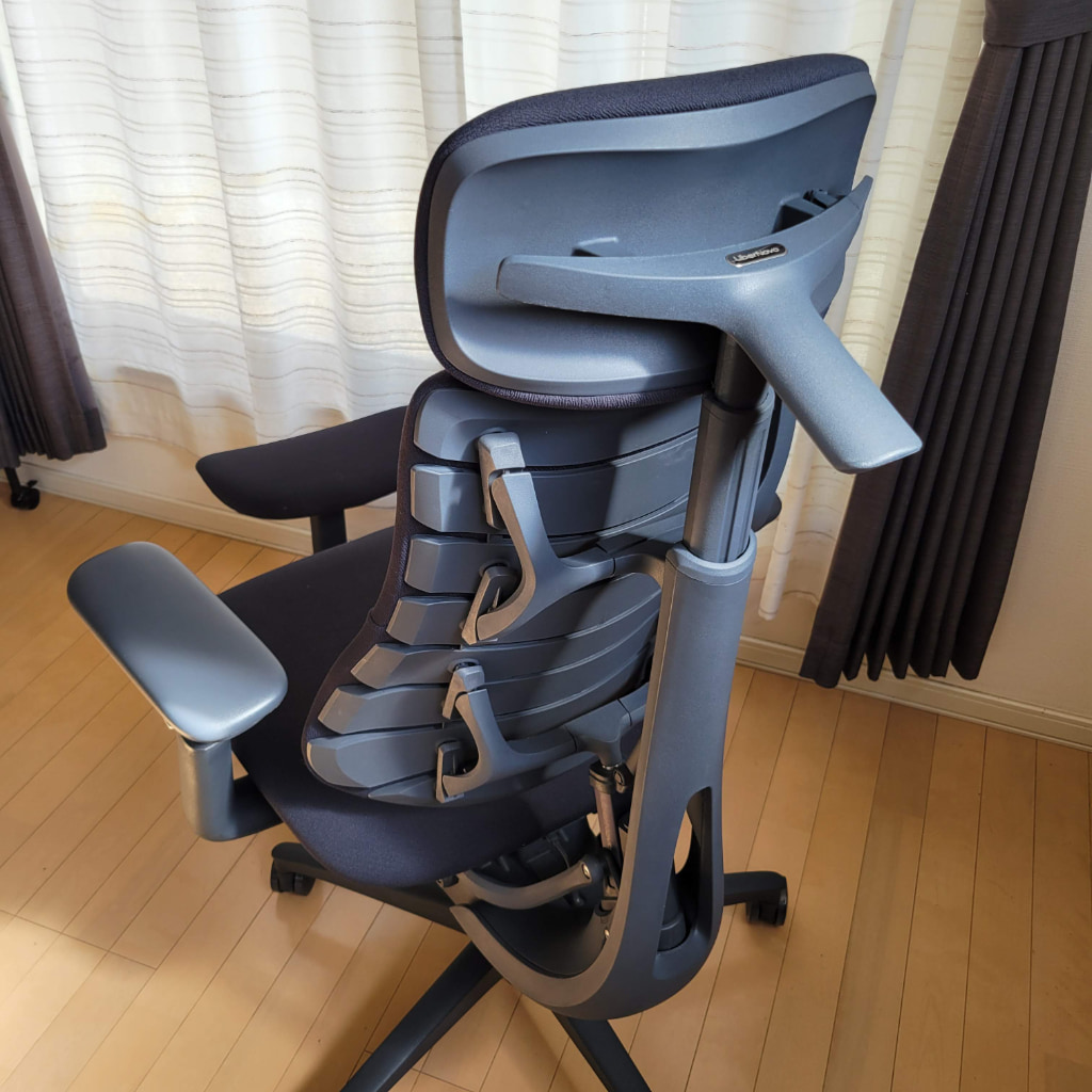 青色と黒色の高機能オフィスチェアが、木製床の部屋に置かれている。